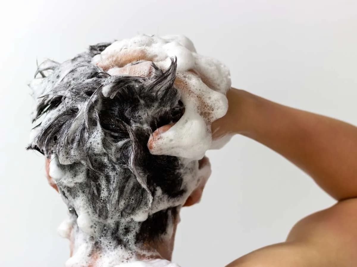 Close-up of a man washing his hair with shampoo, representing the hair regrowth journey for Filipino men and what to expect over time.