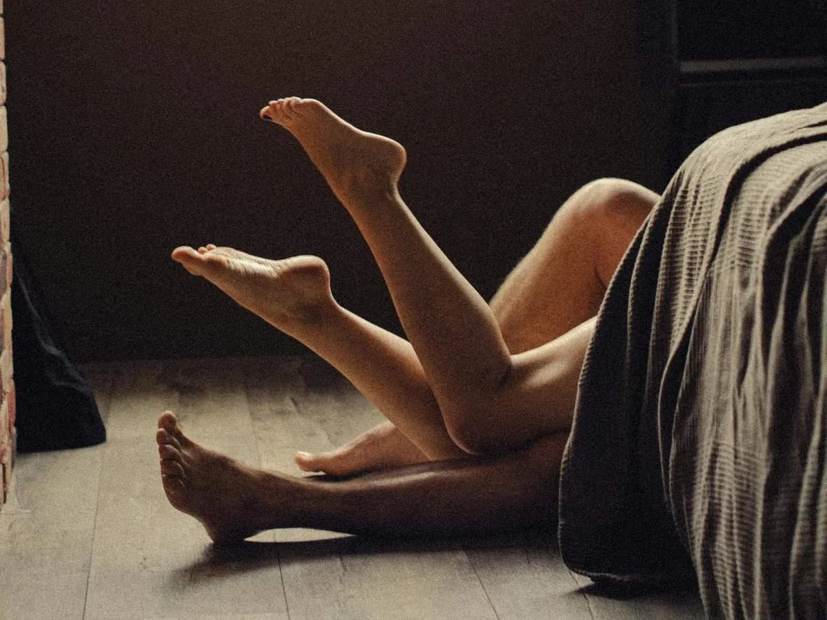 Couple in bed with intertwined legs. Discover science-backed techniques for lasting longer in bed, tailored for Filipino men, at andyou.ph.